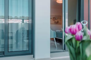 Ein modernes Interieur mit Glastür, einem petrolfarbenen Sofa und einem Gemälde an der Wand.