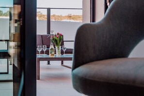 Ein modernes Interieur mit einer Couch, einem Glastisch und Blick ins Freie.