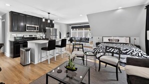Un appartement moderne comprenant une cuisine, un coin repas et une chambre à coucher avec une couvre-lit à motifs zébrés.