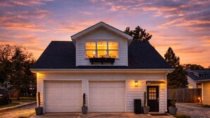 Une maison à deux étages avec un garage, une véranda à l’avant et une boîte aux lettres.