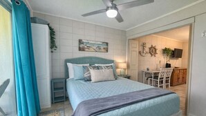 A bedroom with a bed, a ceiling fan, a painting, a desk, and a chair. - SandCastle - Entertainment District - Near Beach (South Padre Island)