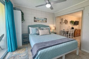A bedroom with a bed, a ceiling fan, a painting, a desk, and a chair. - SandCastle - Entertainment District - Near Beach (South Padre Island)