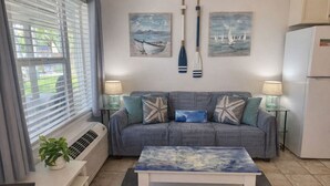 A living room with a sofa, a coffee table, a potted plant, and wall art. - SandCastle - Entertainment District - Near Beach (South Padre Island)