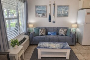A living room with a sofa, a coffee table, a potted plant, and wall art. - SandCastle - Entertainment District - Near Beach (South Padre Island)