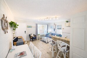 A compact living space with a dining area, a sofa, and a kitchen counter. - SandCastle - Entertainment District - Near Beach (South Padre Island)