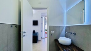 A modern bathroom with a built-in sink, a mirror, and a door leading to a hallway.
