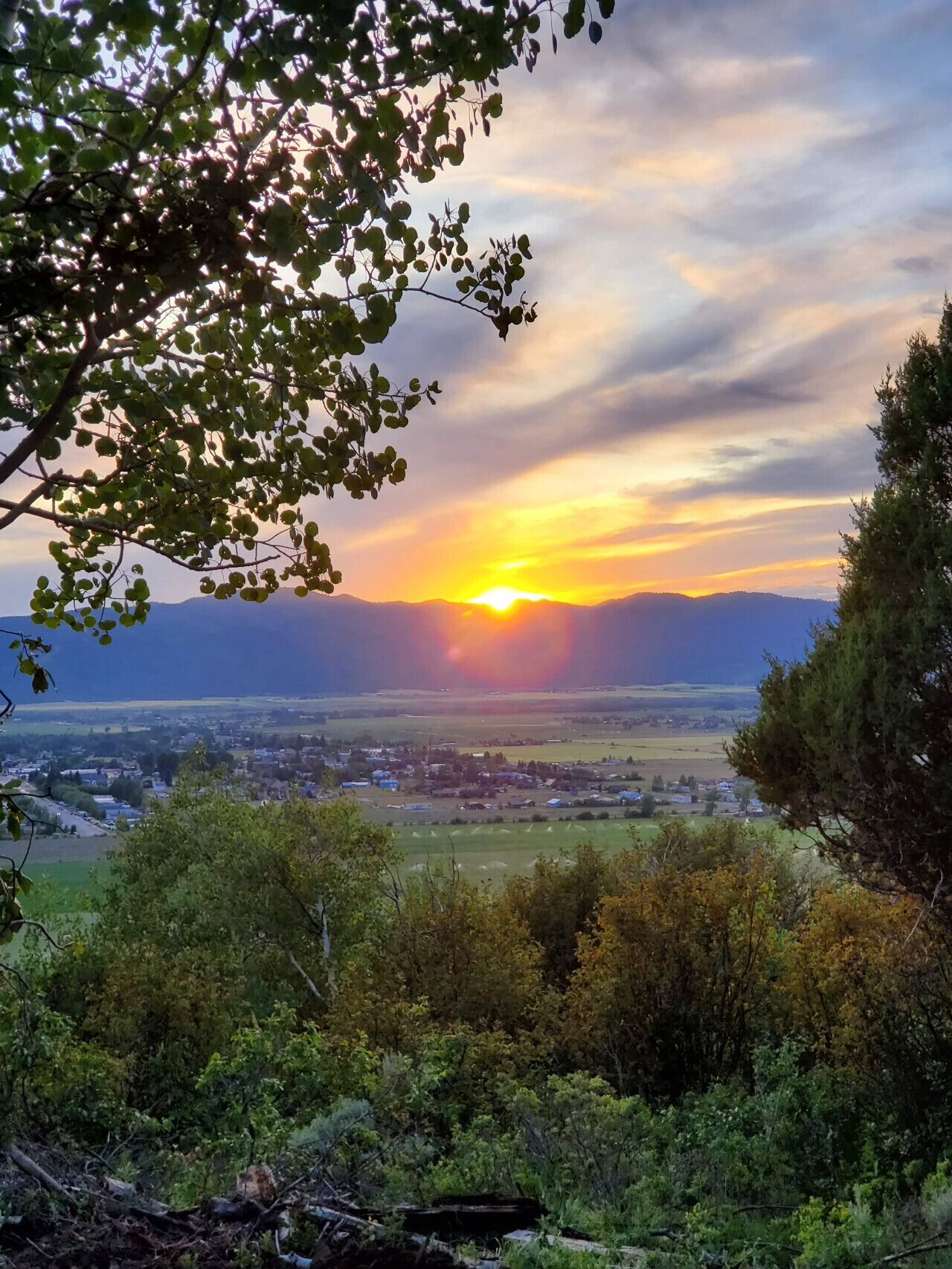 A sunset over a valley with a town in the distance.