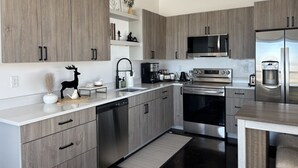 A modern kitchen with grey cabinetry, stainless steel appliances, and a built-in microwave. - Luxury home with hot tub (Victor)