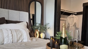 A bedroom with a bed, a bedside table with candles, a mirror, and a robe hanging on a rack. - Luxury home with hot tub (Victor)