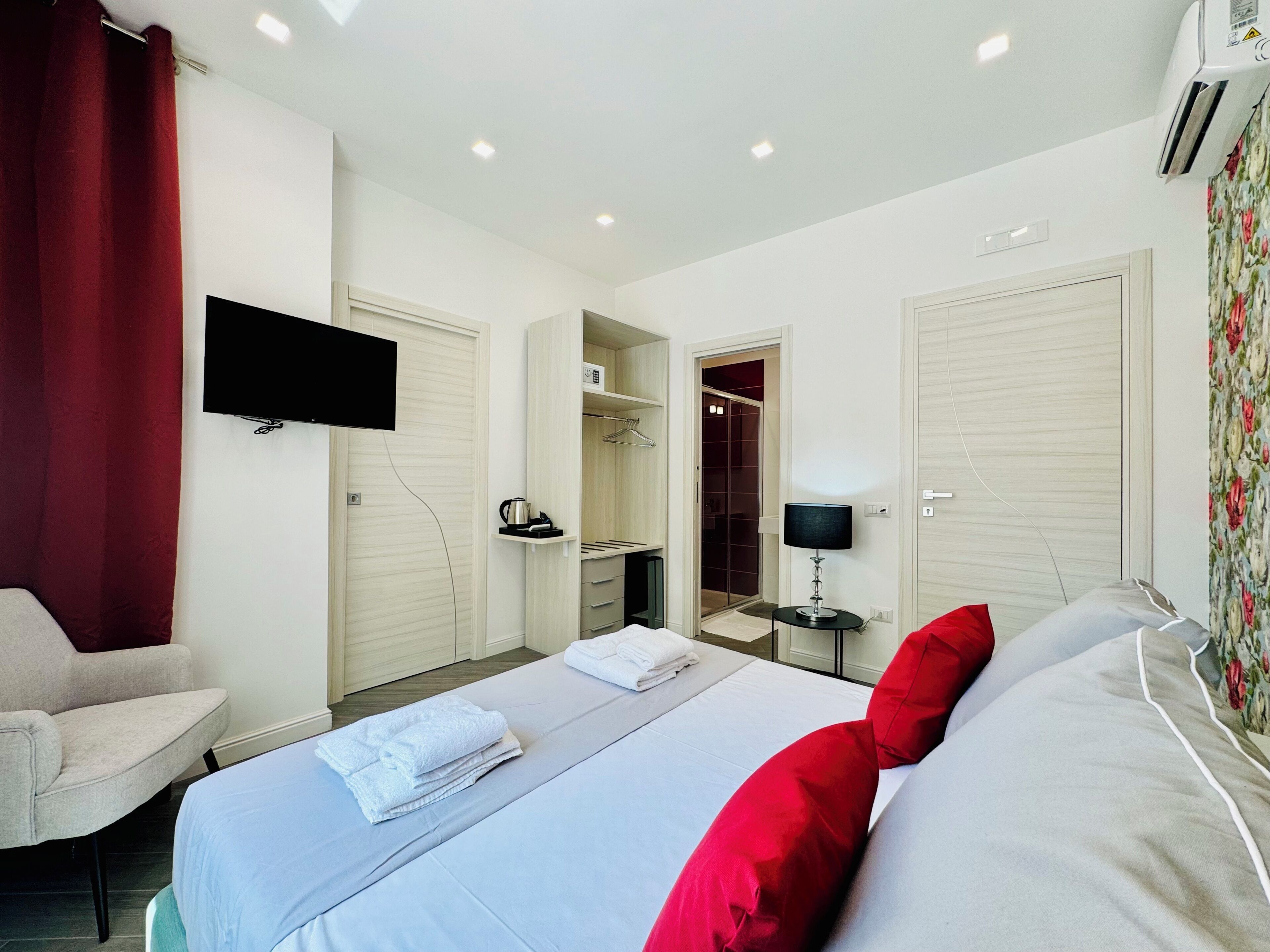 A hotel room with a bed, a TV, a desk, a chair, and a wardrobe.