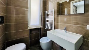 Un baño moderno con un lavamanos grande, un inodoro, un bidé y una ventana.