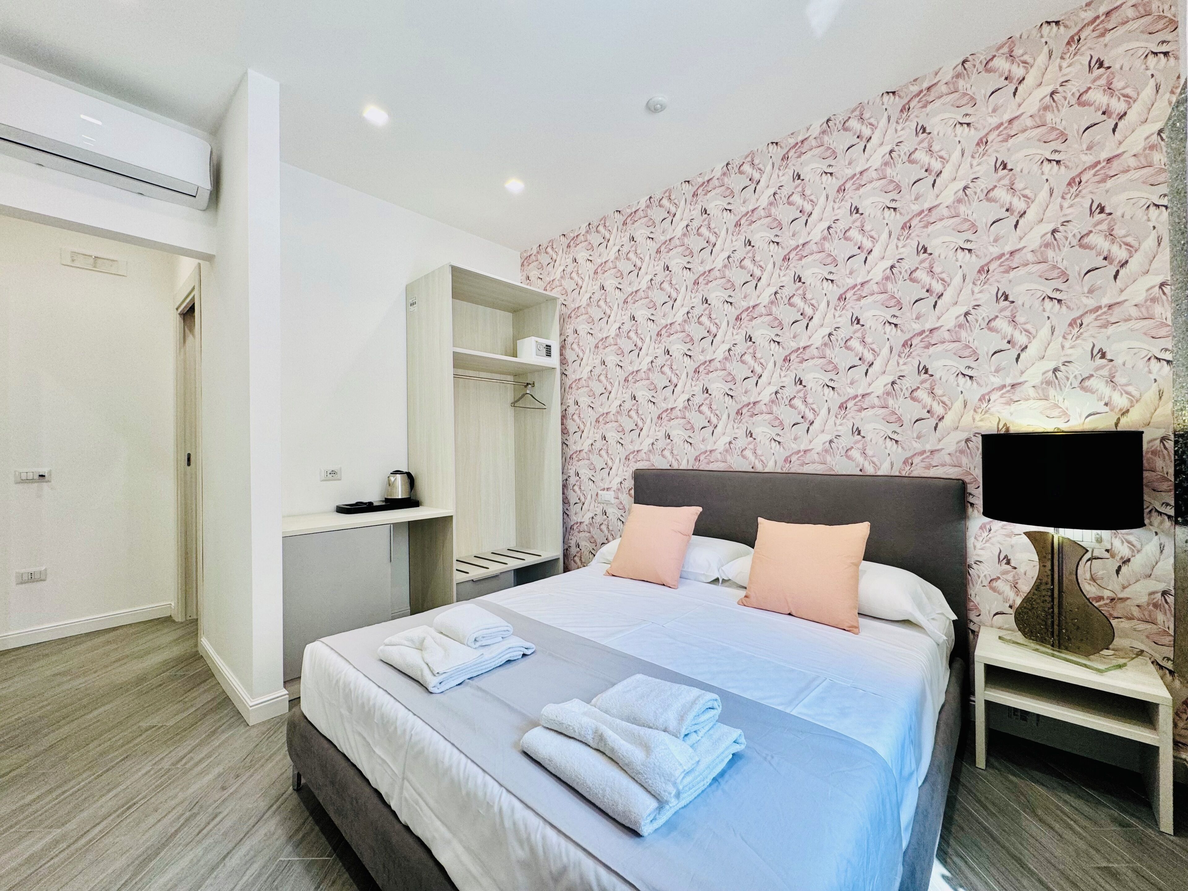 Ein Hotelzimmer mit Bett, Nachttisch, Fernseher, Kleiderschrank und Duschbereich.