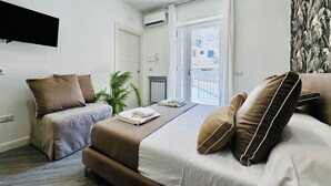 Un cuarto de hotel moderno con una cama, dos mesitas de noche, una planta en maceta y vistas al exterior.