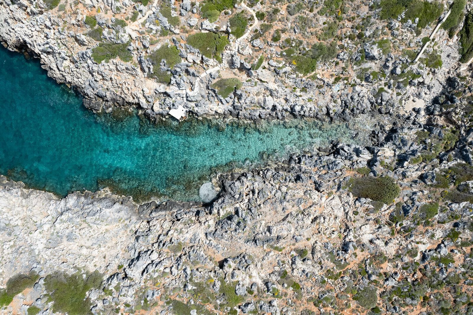 A rugged coastline with rocky terrain and clear turquoise waters.
