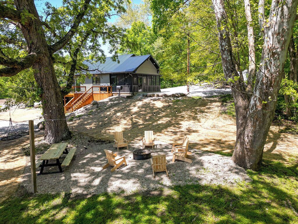 Eine Hütte mit einer Terrasse, umgeben von Bäumen und Sitzgelegenheiten im Freien.
