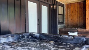 A hot tub area with wooden beams, a black wall, and a window.