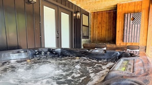 A hot tub with a control panel, wooden walls, and a view of the outside.