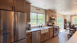 A kitchen with stainless steel appliances, wooden cabinets, a built-in oven, and a window providing natural light.