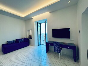 Una habitación moderna con sofá, escritorio, silla y televisor montado en la pared.