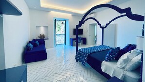 A modern bedroom with a bed, a desk, and a seating area. - YourHome - Scirocco Suite (Sorrento)