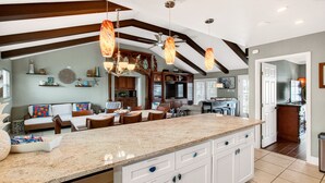 A spacious kitchen with a large island, white cabinetry, and a ceiling fan. - Waterfront Retreat w/ Pool, Dock & Fire Pit (Rockport)