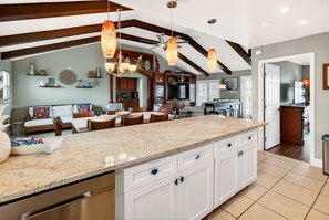 A spacious kitchen with a large island, white cabinetry, and a ceiling fan. - Waterfront Retreat w/ Pool, Dock & Fire Pit (Rockport)