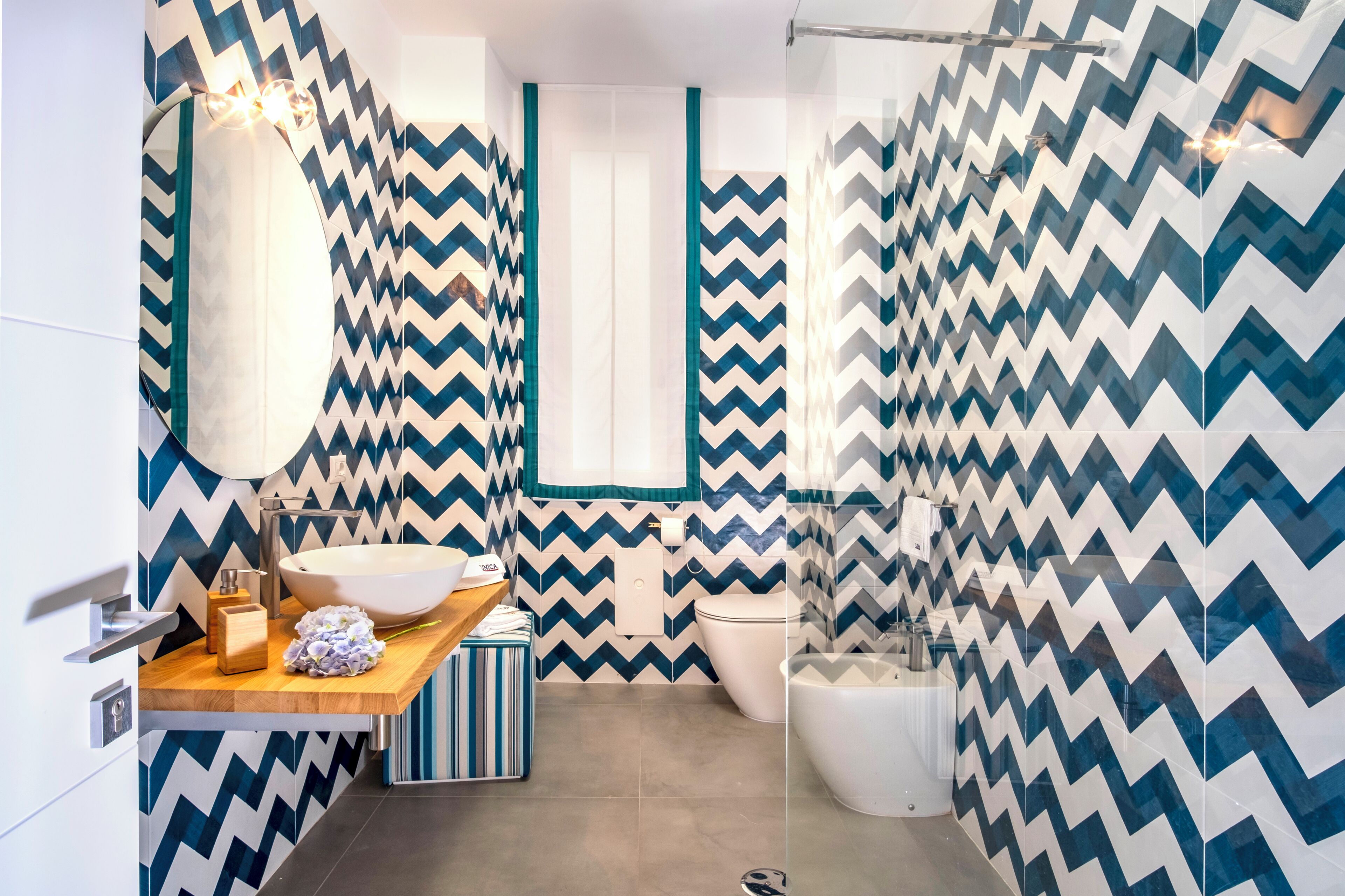 A modern bathroom with a large white sink, a mirror, and a shower area.