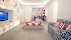 Ein modernes Wohnzimmer mit Sofa, Hocker, Fernseher und maßgefertigten Regalen.