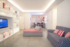 Ein modernes Wohnzimmer mit Sofa, Hocker, Fernseher und maßgefertigten Regalen.