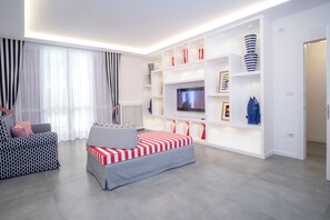 Ein modernes Wohnzimmer mit einer Couch, einem Fernseher und eingebauten Regalen mit Dekorationselementen.