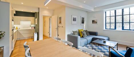 A modern living space with a dining area, kitchen, and seating area.