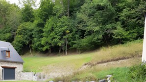A stone wall, a paved driveway, and a house with a garage. - Chalet for 10-12 Guests, 10 min from Peyragudes and Loudenvielle (Cazaux-Fréchet-Anéran-Camors)