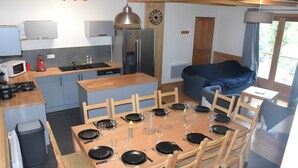 A modern kitchen with a dining area, wooden furniture, and a large window. - Chalet for 10-12 Guests, 10 min from Peyragudes and Loudenvielle (Cazaux-Fréchet-Anéran-Camors)