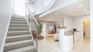 Un intérieur moderne avec un escalier en colimaçon, un îlot de cuisine et un téléviseur à écran plat.