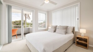 Une chambre avec un grand lit, une table de chevet, une chaise et un balcon avec vue.