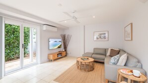 Un salon moderne avec un canapé, une table basse et un téléviseur.