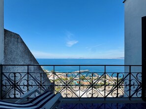 Ein Balkon mit schmiedeeisernem Geländer und Blick auf die Küste.
