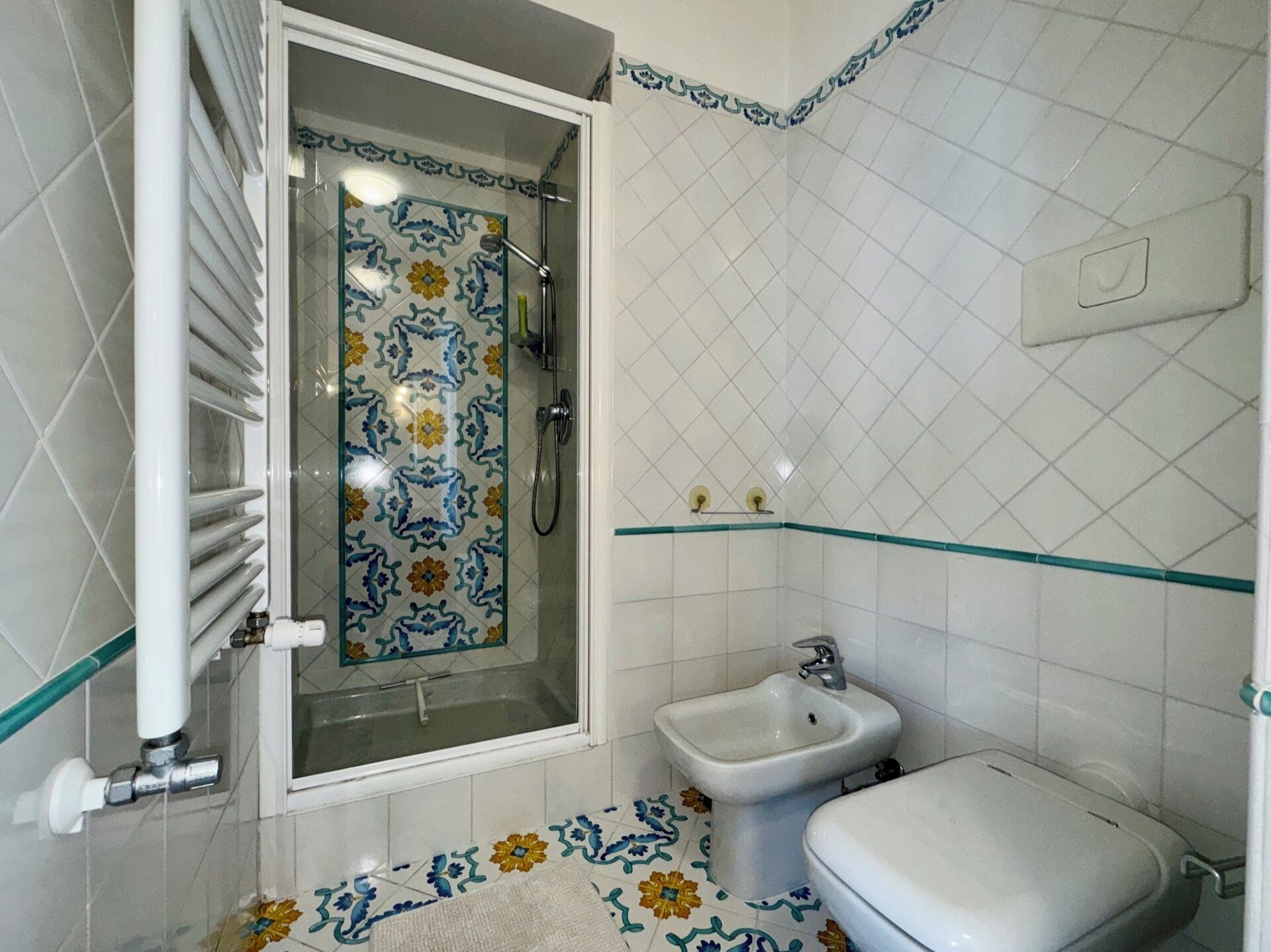 Ein Badezimmer mit Dusche, Bidet, Toilette und Fliesenboden.