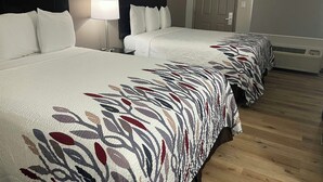 Habitación de hotel con dos camas, una mesita de noche con lámpara, una puerta y un equipo de aire acondicionado.