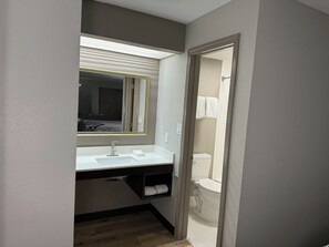 Een badkamer met een witte wastafel, een spiegel en een toilet.