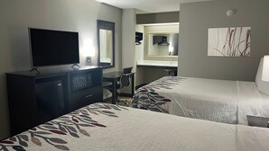 A hotel room with two beds, a desk, a television, a mirror, and a bathroom. - Red Roof Inn Helen, GA - Downtown (Helen)