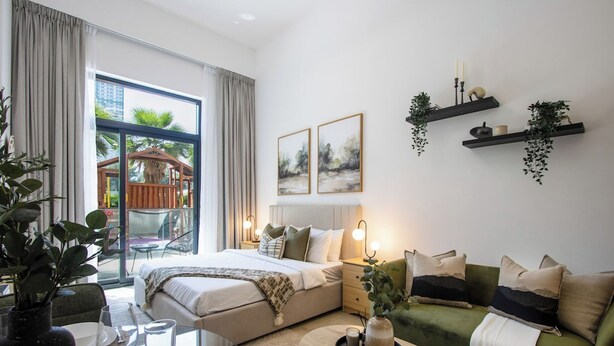 Ein modernes Hotelzimmer mit Bett, Sofa, Glastisch und einem Balkon mit Blick.