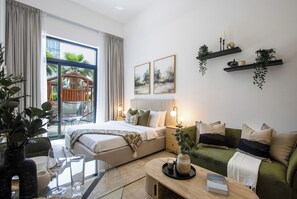 A modern hotel room with a bed, sofa, glass table, and a balcony with a view. - Brand New Stay | Low Floor with Pool, Gym Access (Dubai)