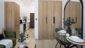Ein modernes Wohnzimmer mit einem Glastisch, einer Couch und einer Küche im Hintergrund.