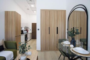 Una sala moderna con una mesa de vidrio, un sofá y una cocina al fondo.
