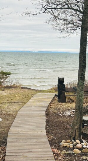 A wooden boardwalk leading to a bear statue by the water.
