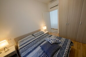 Ein Schlafzimmer mit Bett, Nachttischlampen, einem Kleiderschrank und einer Klimaanlage.