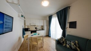 Un espacio habitable compacto con kitchenette, comedor y sofá.