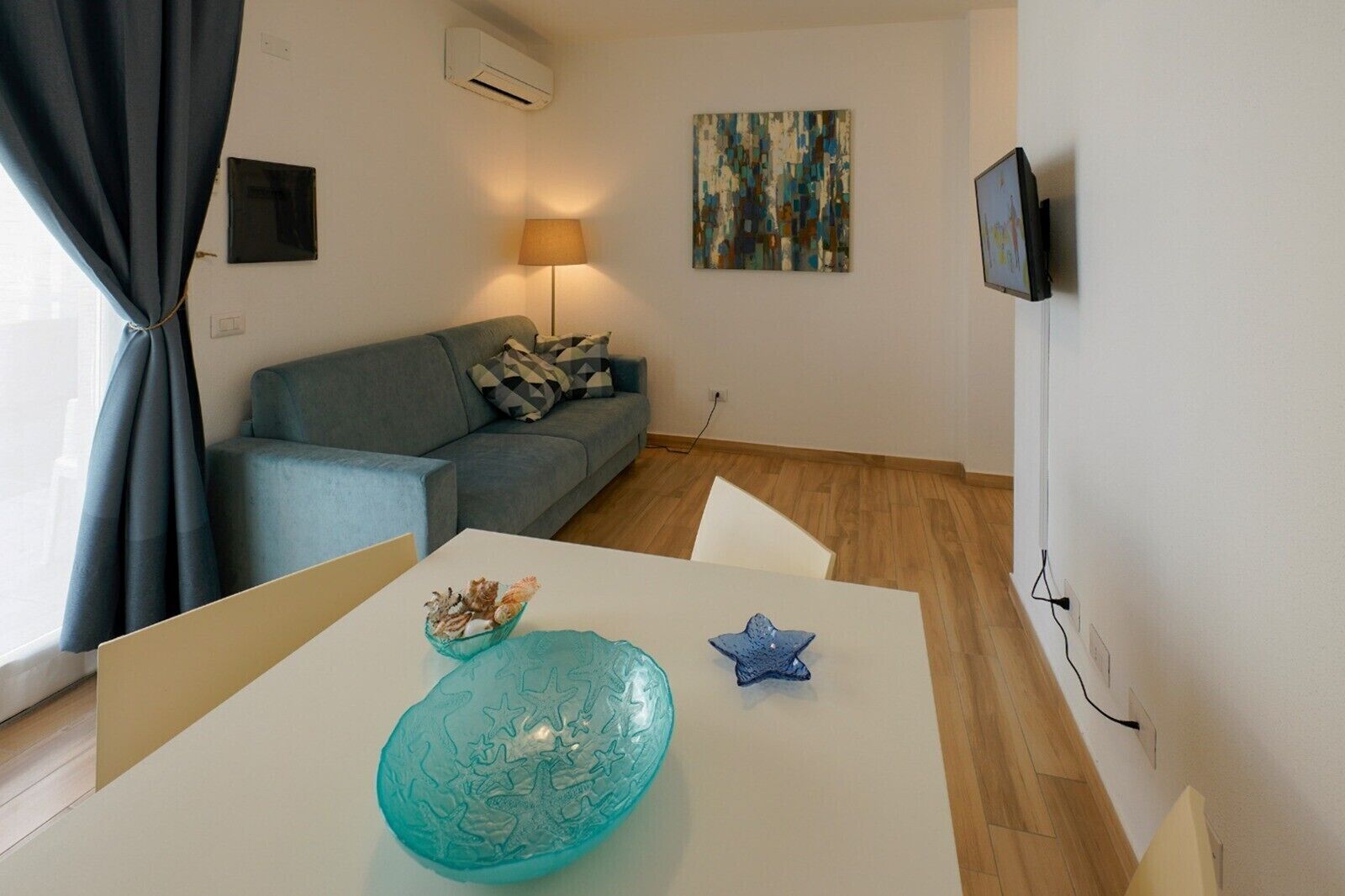 Ein Wohnzimmer mit einer Couch, einem Tisch mit Dekoration, einer Lampe und einem Bild an der Wand.