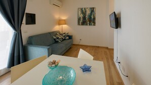 Una sala de estar con un sofá, una mesa con adornos, una lámpara y un cuadro en la pared.